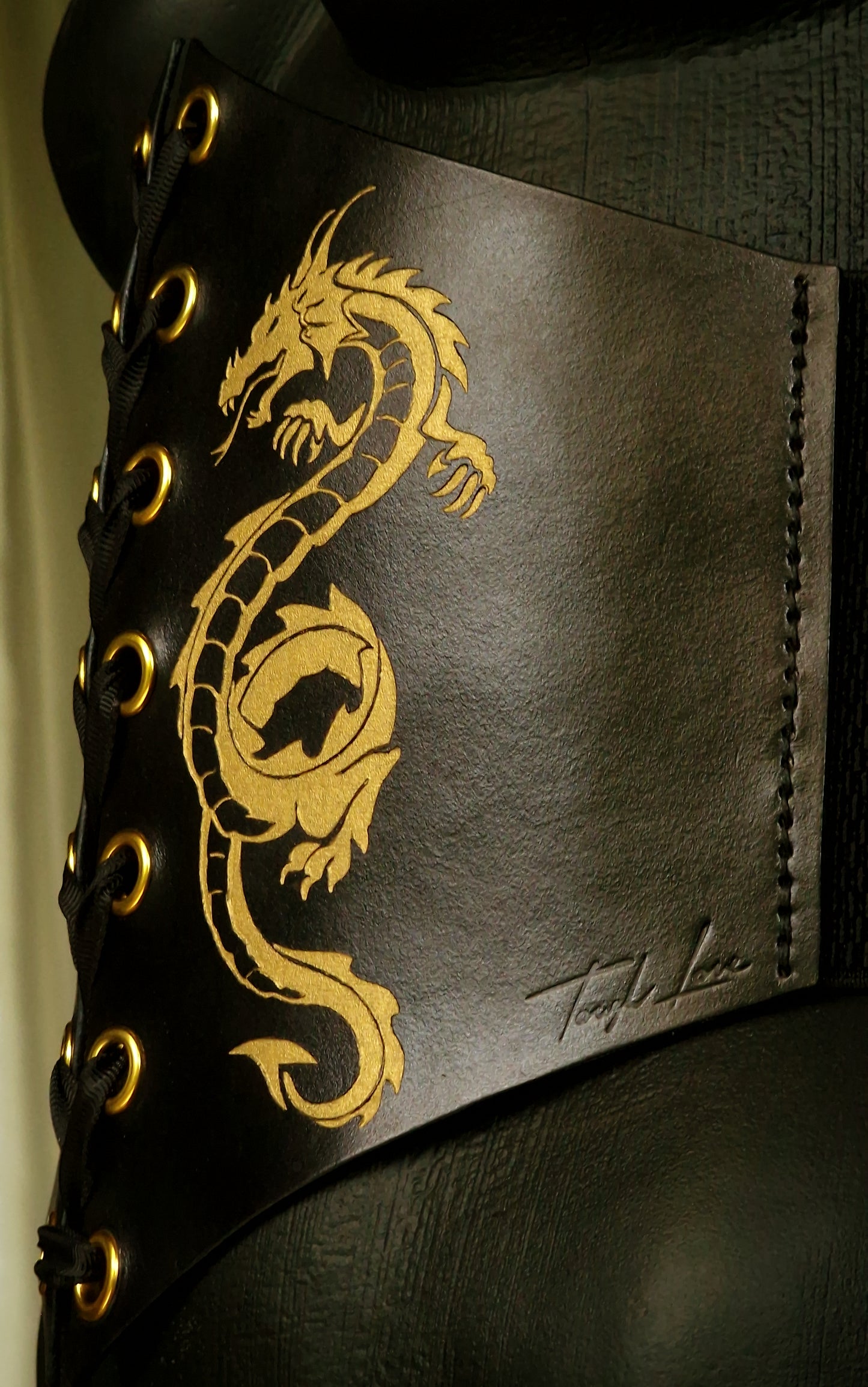 Dominatrix wearing handmade Tough Love leather corset with golden dragon engraving