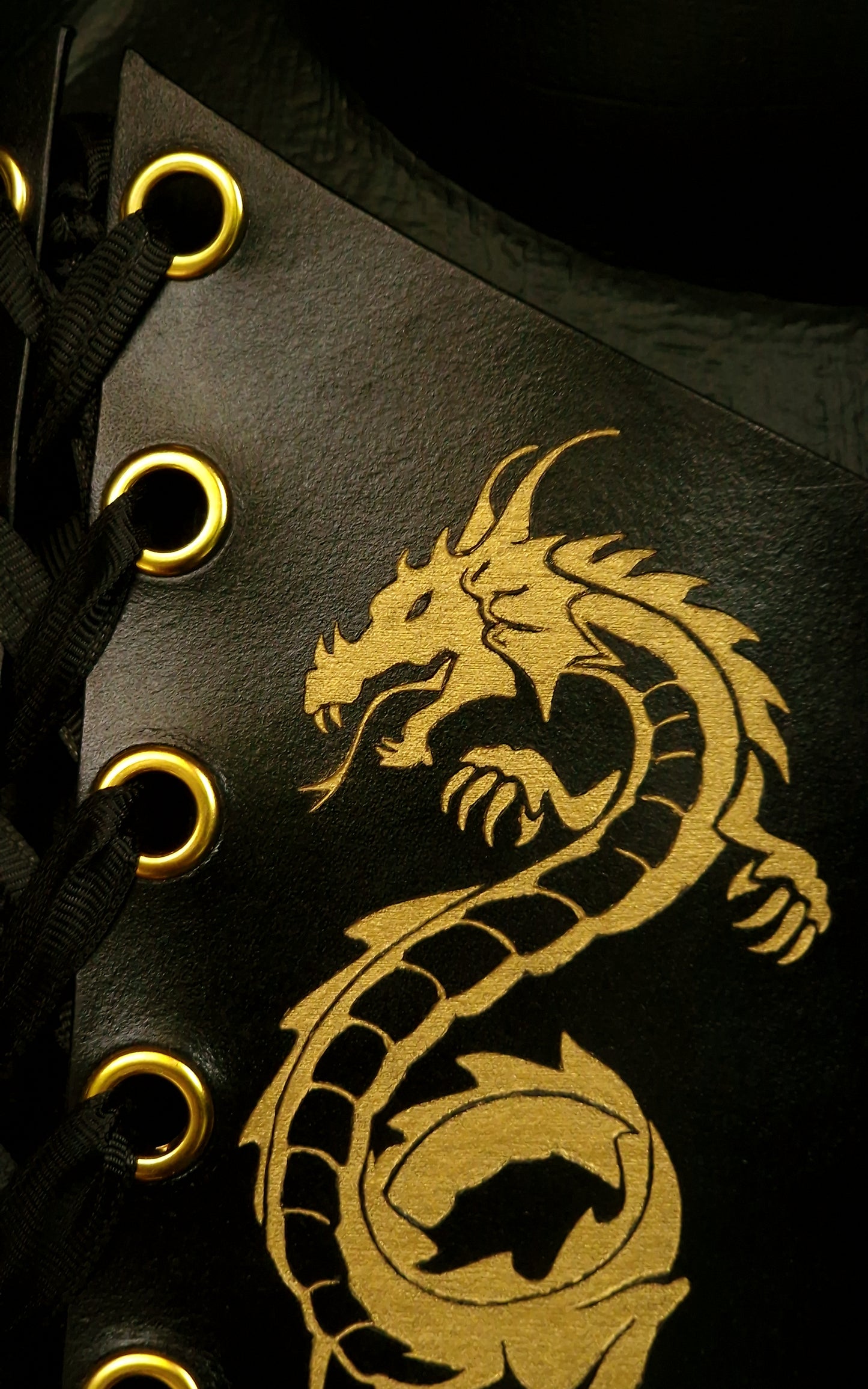 Detail of engraved and hand-painted golden dragon on vegetable-tanned leather corset front
