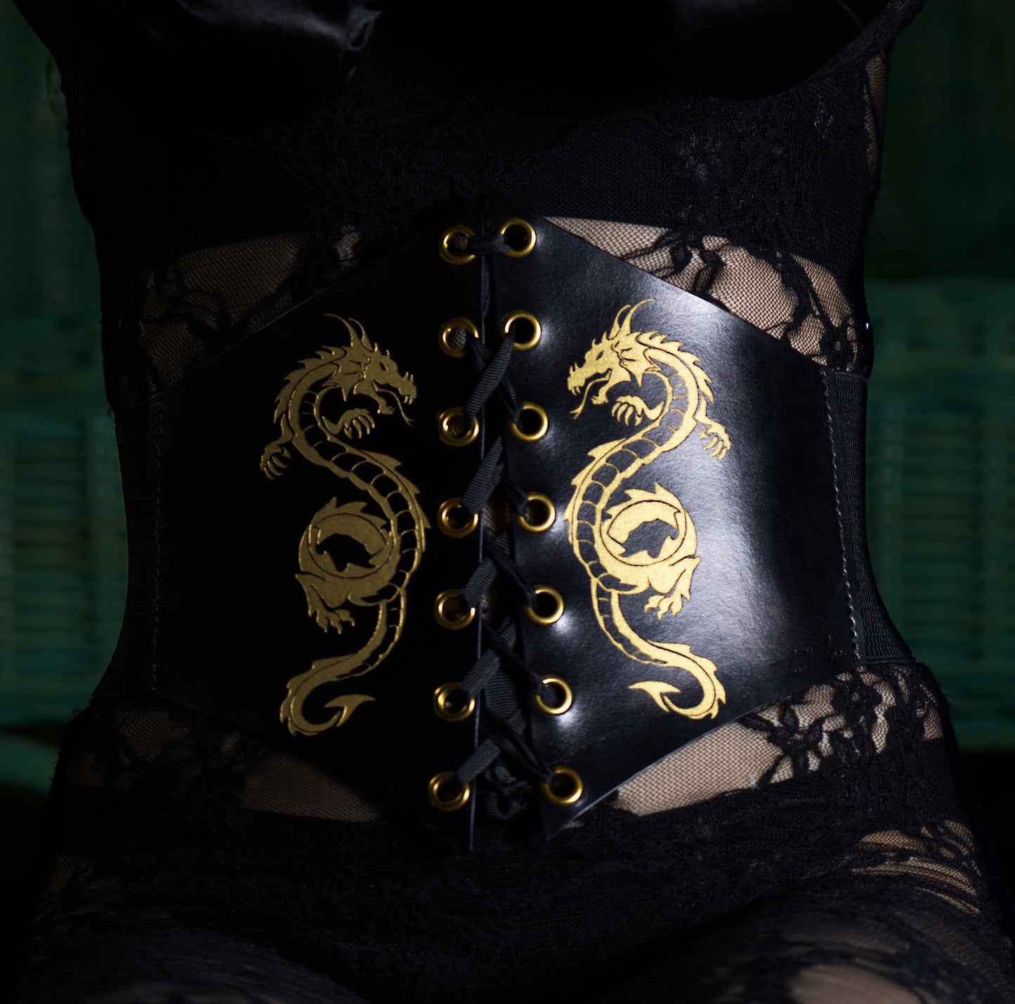 Front view of handmade BDSM leather corset worn by dominatrix, featuring front lacing and engraved ornament