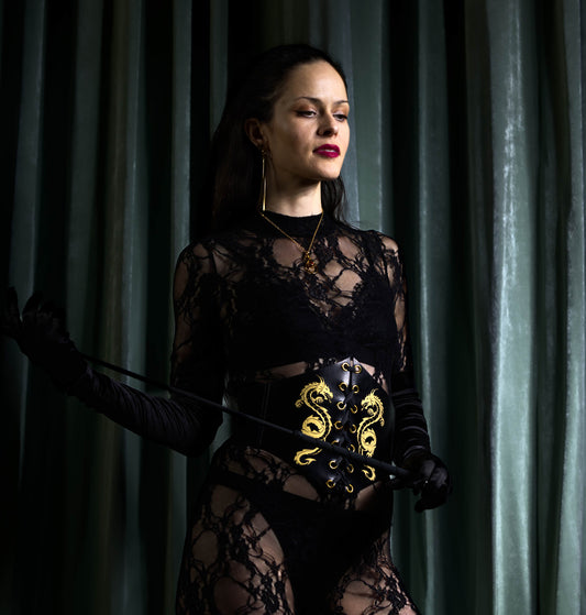 Dominatrix wearing handmade vegetable-tanned leather corset with golden dragon engraving and front lacing